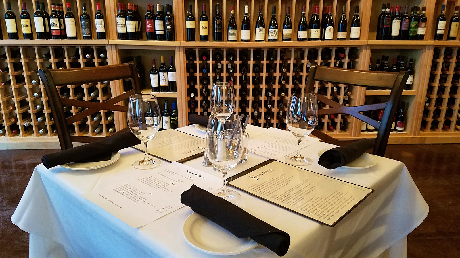 Four wineglasses on a set table with menus